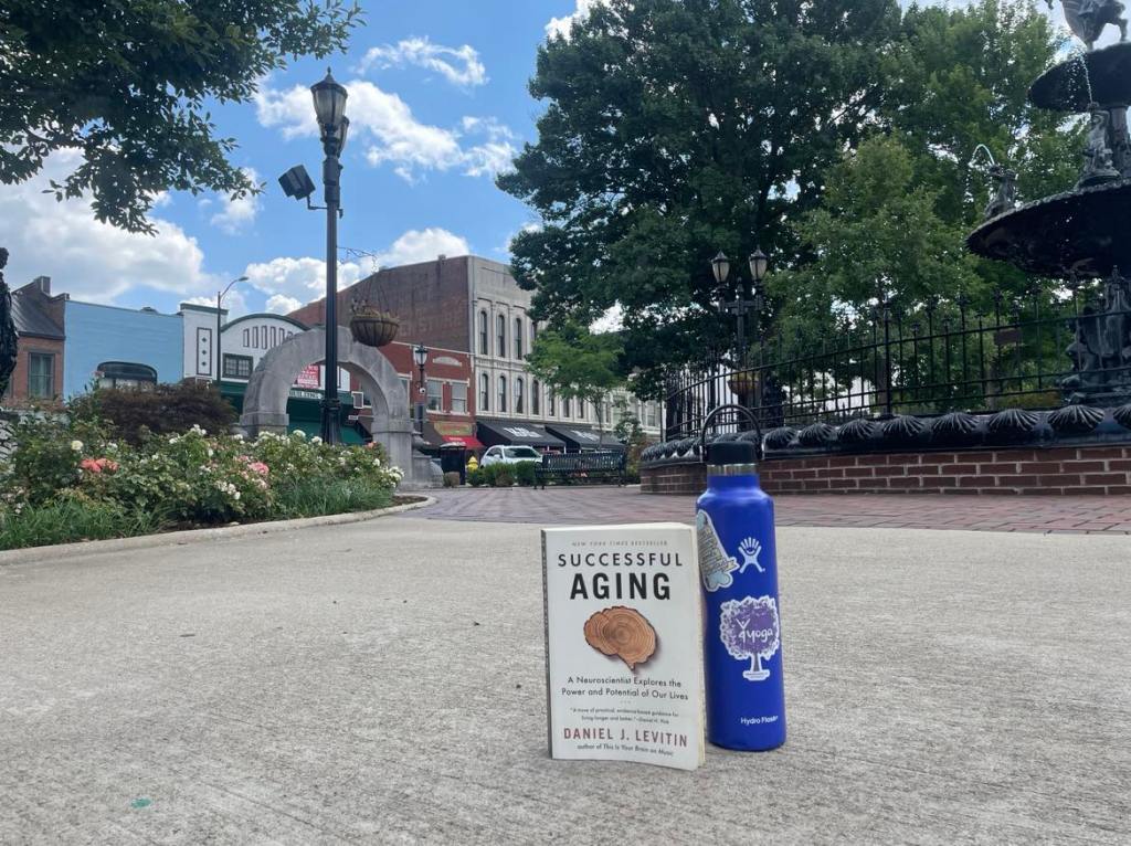 Photo of Successful Aging book and water bottle with 4yoga sticker in Circus Square Park.